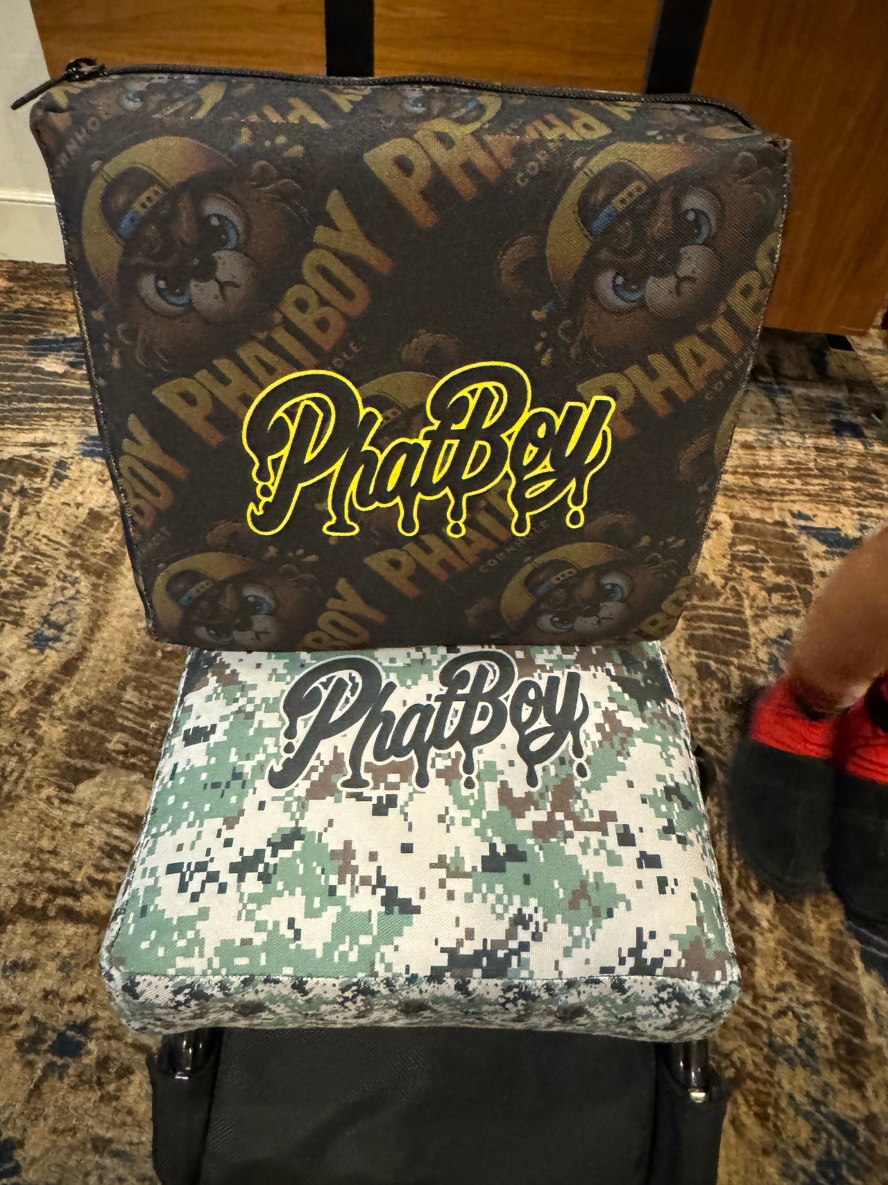Two Phatboy pouches with a brand logo on a patterned surface